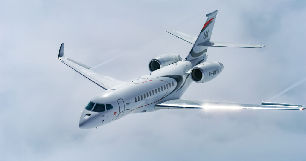 Dassault Falcon 6X blanc volant à travers les nuages – Technologie ultra-widebody révolutionnaire et confort exceptionnel chez FA Aircraft Sales.