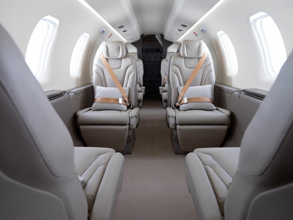 Intérieur de luxe d'un Pilatus PC-24 avec sièges en cuir gris — Design moderne et confort spacieux pour les voyageurs d'affaires via FA Aircraft Sales.